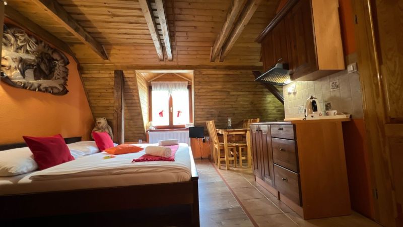 Holzbalken, Bett, Küchenzeile und Tisch im Dachgeschoss der Villa.