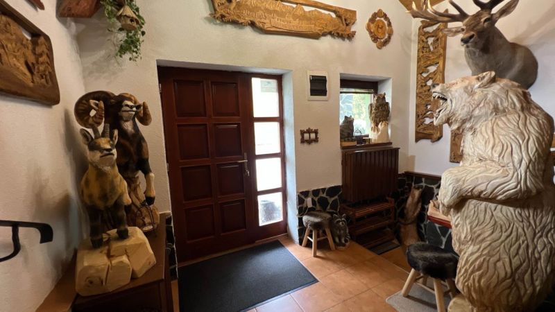 Das Innere der Villa mit hölzernen Tierskulpturen und geschnitzten Verzierungen an den Wänden.