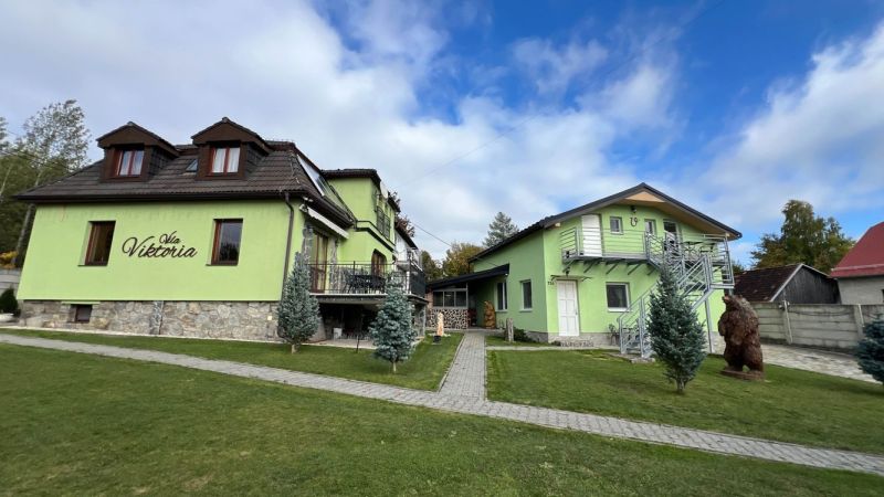 Eine Villa in Štôla, Bezirk Poprad, Region Prešov, Slowakei, mit grüner Fassade und einem sorgfältig gepflegten Garten.