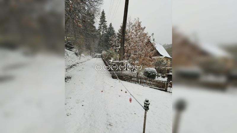 Eine verschneite Straße in Horné Otrokovce mit einem Einfamilienhaus und einem Zaun.