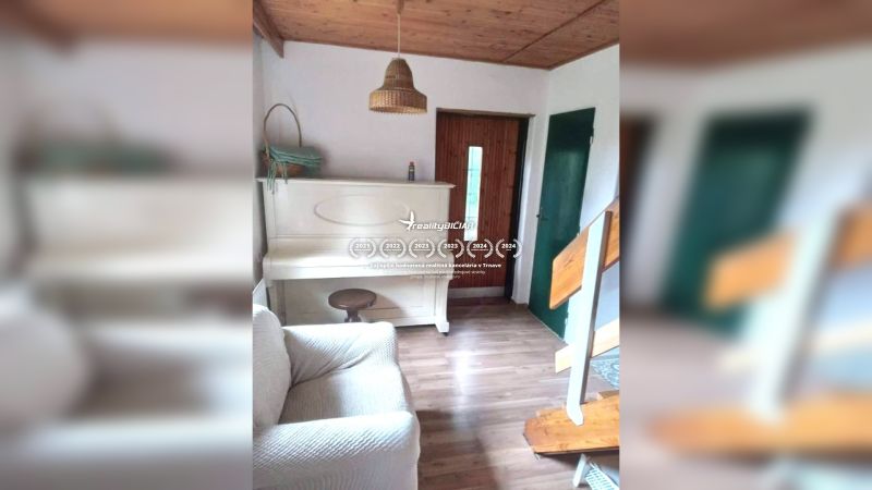 Innenraum eines Einfamilienhauses mit weißem Klavier, Holzboden, Treppe und Holzdecke.