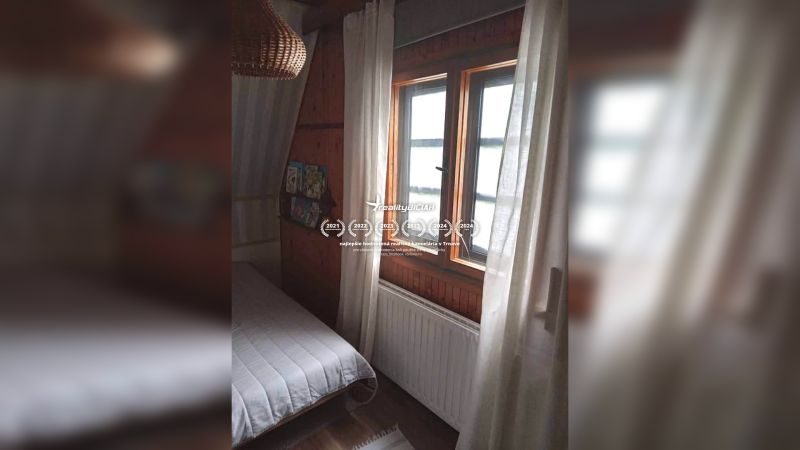 Ein Zimmer in einem Einfamilienhaus mit dunkler Holzverkleidung und einem Bett am Fenster.