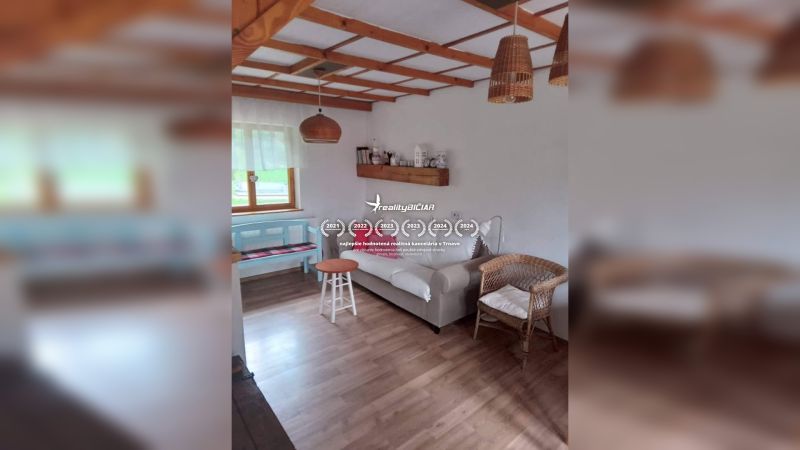 Ein Interieur in einem Einfamilienhaus mit einem Boden in Holzoptik, einem Rattansessel und einem Sofa.