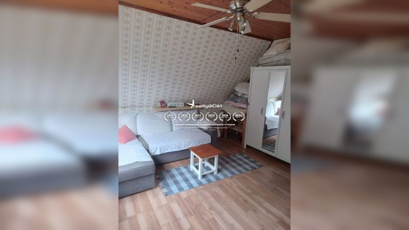 Dachzimmer in einem Einfamilienhaus mit Sofa, Teppich und Holzboden.