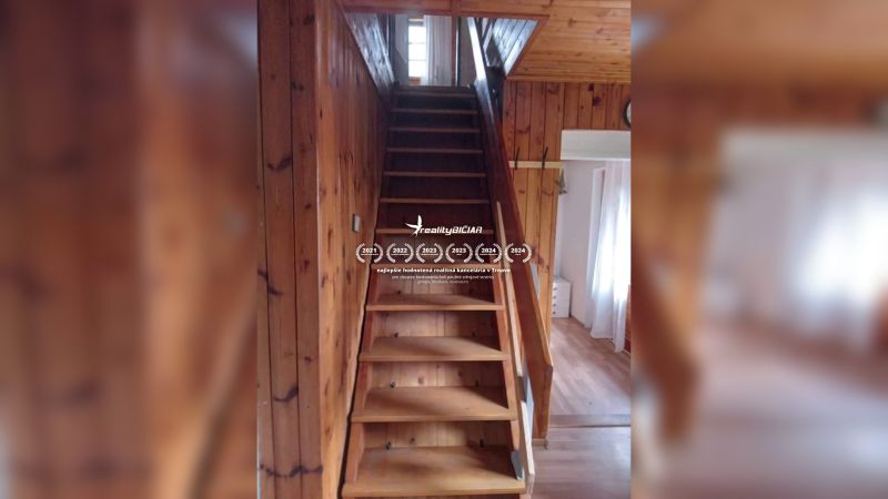 Eine Holztreppe führt in einem Einfamilienhaus mit einem Boden in Holzoptik in den ersten Stock.