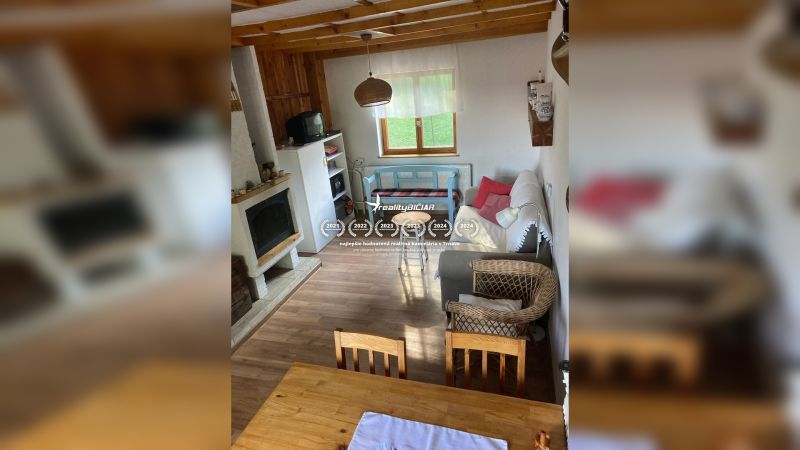 Wohnzimmer in einem Einfamilienhaus mit Kamin, Sessel und Boden in Holzoptik.