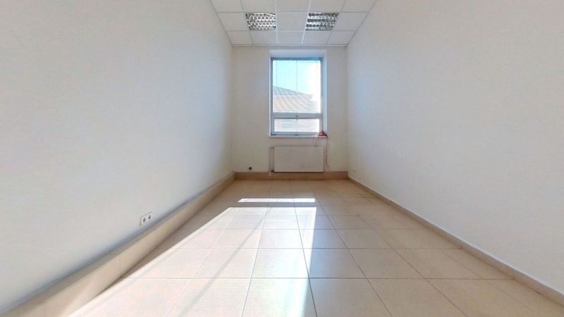 Ein klares Büro mit gefliestem Boden und einem großen Fenster, das Licht hereinlässt.