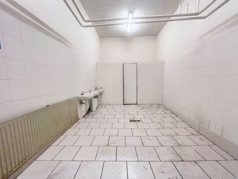 Innenräume von Lagern und Hallen mit weißen Wänden, zwei Waschbecken und gefliestem Boden.