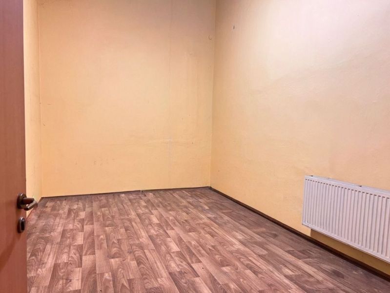 Ein Raum mit einem Holzboden, gelben Wänden und einem Heizkörper in Lager- und Industriehallen.