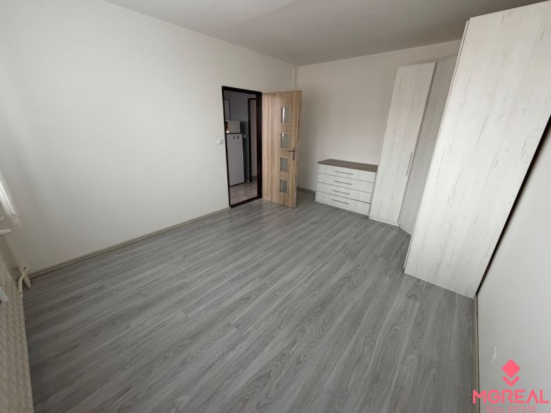 Ein Zimmer mit Holzboden, Schränken und einer Kommode in einer Einzimmerwohnung.
