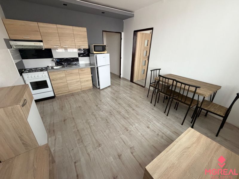 Küche mit Holzelementen und Esstisch in einer Einzimmerwohnung.