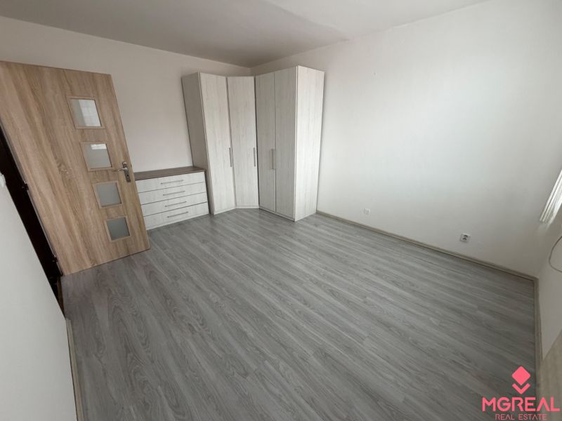 Ein Zimmer in einer Einzimmerwohnung mit einem Holzboden und einem Einbauschrank.
