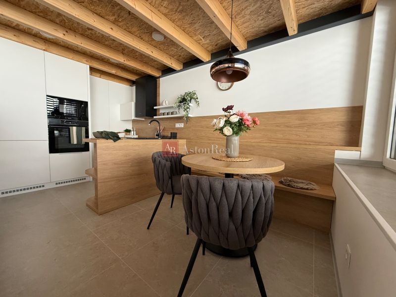 Eine Küche in einem Einfamilienhaus mit einer Holzdecke, einem Boden mit Holzdekor und stilvollen Sitzgelegenheiten.