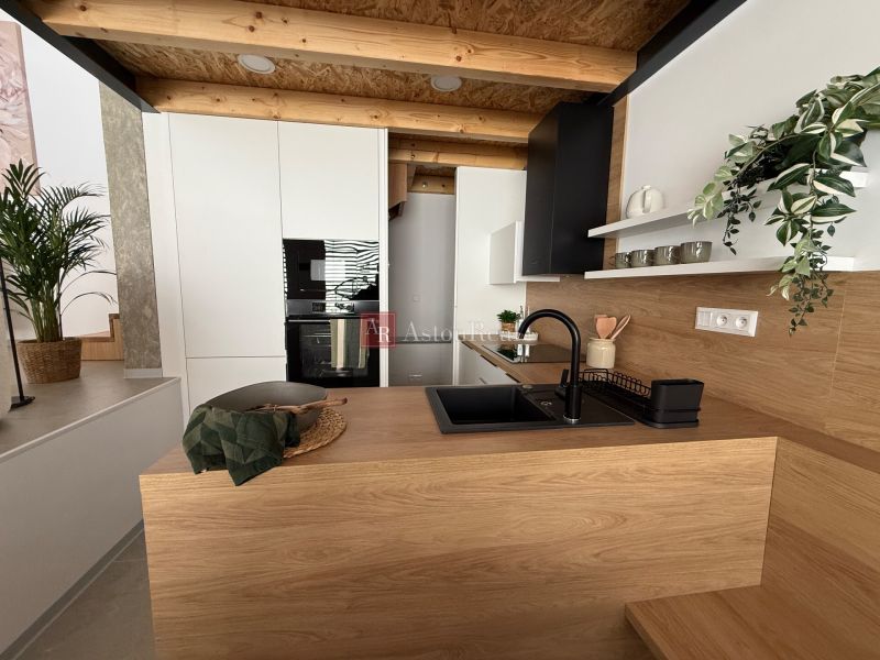 Moderne Küche in einem Einfamilienhaus mit Holzdekor und schwarzem Spülbecken.