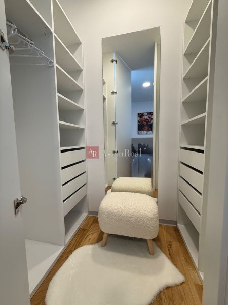 Ein Einfamilienhaus mit einem Kleiderschrank, einem Boden in Holzoptik und einem bequemen Stuhl.