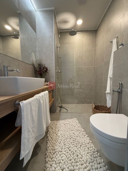 Badezimmer in einem Einfamilienhaus mit offener Dusche, Waschbecken und dekorativer Matte.