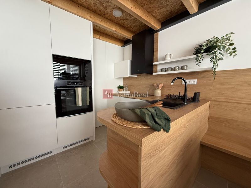Küche in einem Einfamilienhaus mit Holzdekor, weißen Schränken und Pflanzen.
