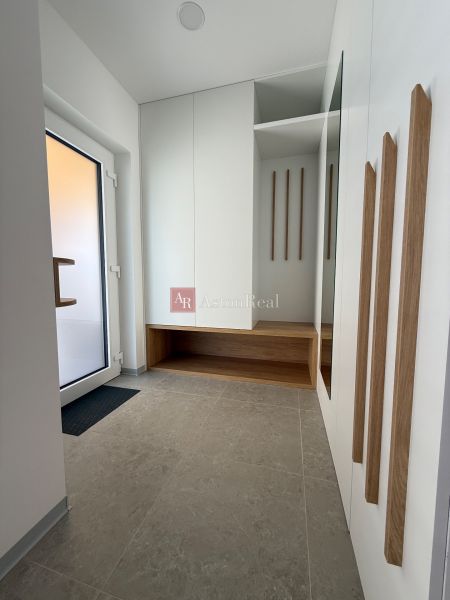 Eingangshalle in einem Einfamilienhaus mit Spiegel, Stauraum und hellen Fliesen.