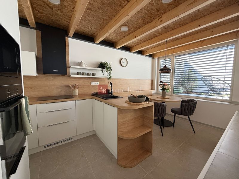 Eine Küche in einem Einfamilienhaus mit Holzboden, Holzbalken und einem Esstisch.