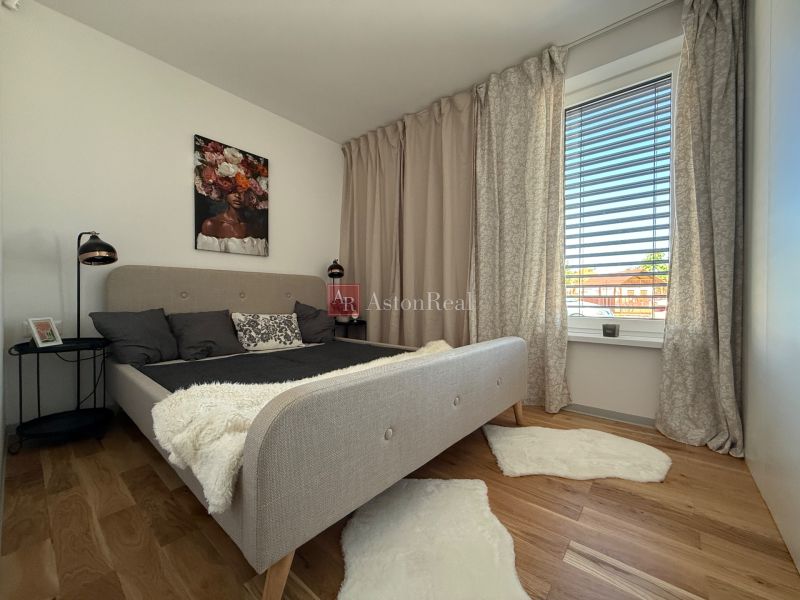 Schlafzimmer mit Bett, Vorhängen, Bild und Boden mit Holzdekor in einem Einfamilienhaus.