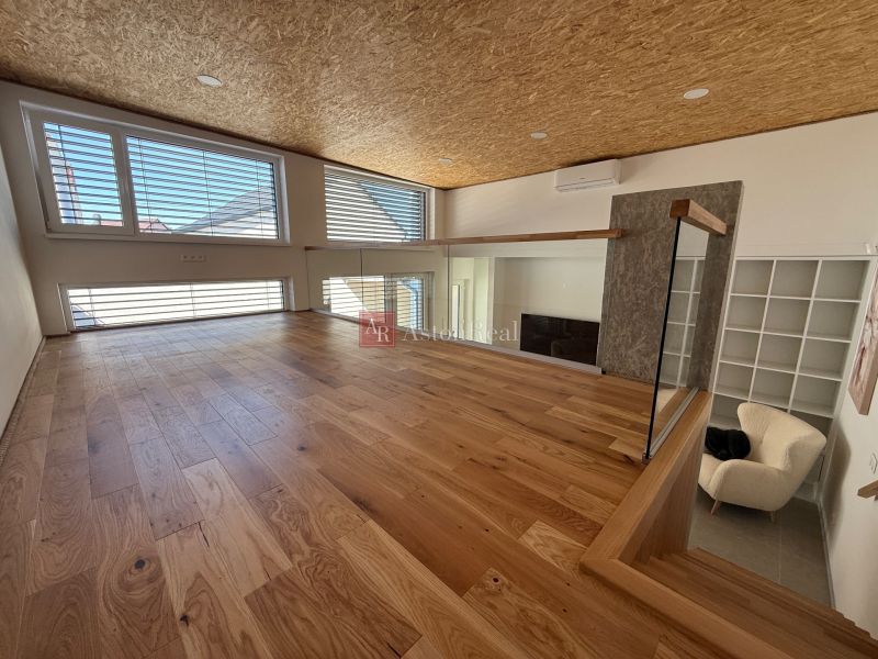 Innenraum eines Einfamilienhauses mit Holzboden und großen Fenstern.