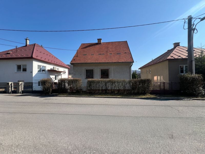 Ein Einfamilienhaus in Banská Bystrica mit rotem Dach und einem Strauchzaun.