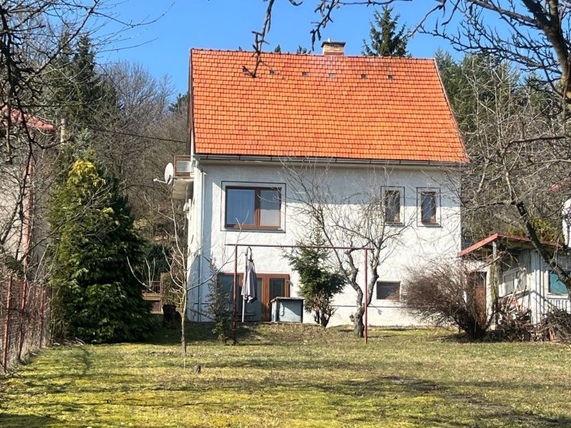 Ein Einfamilienhaus in Kráľová, Banská Bystrica, mit einem roten Dach, umgeben von Grün und Bäumen.