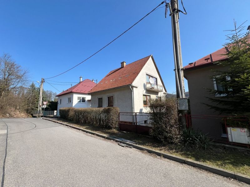 Einfamilienhaus in Podháj, Kráľová, Banská Bystrica. Schmaler Gehweg, Sträucher, Strommast.