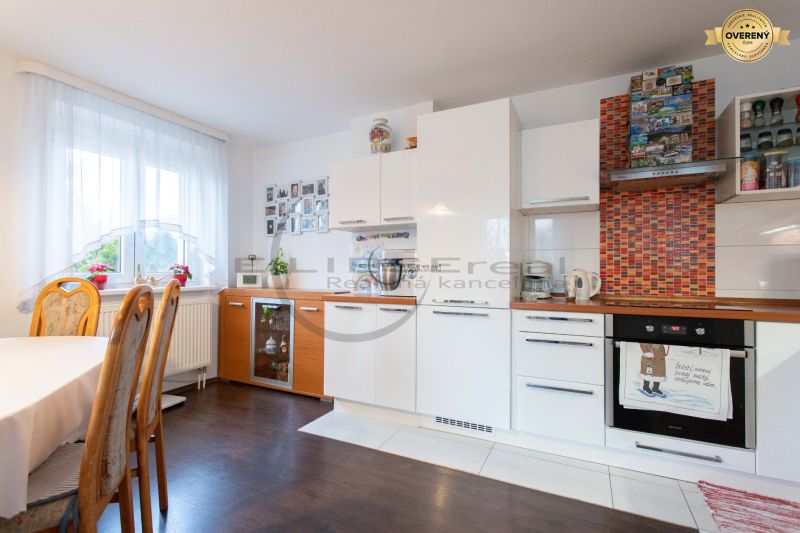 Küche in einem Einfamilienhaus mit weißen Schränken und einem Boden in Holzoptik.
