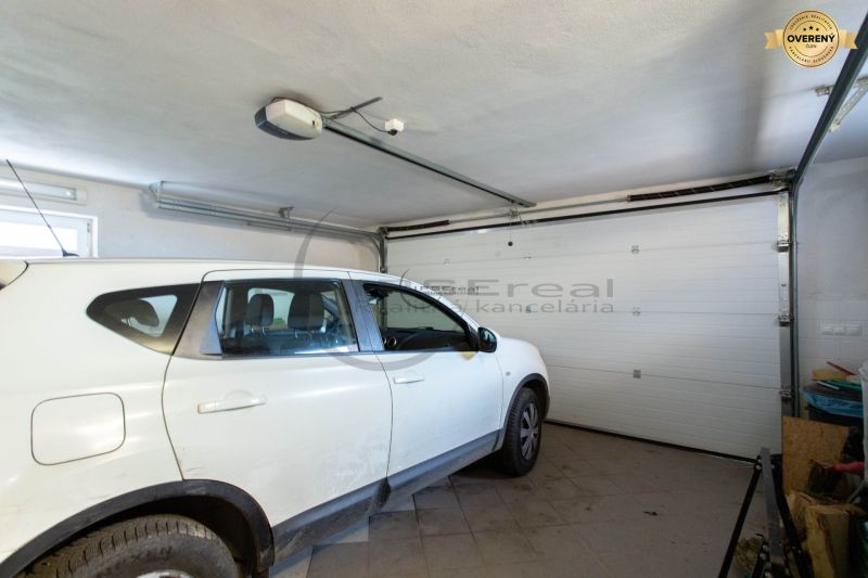 Ein Auto, das in der Garage eines Einfamilienhauses mit weißen Wänden und Fliesenboden geparkt ist.