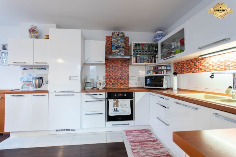 Küche in einem Einfamilienhaus mit weißen Schränken und einem Boden in Holzoptik.