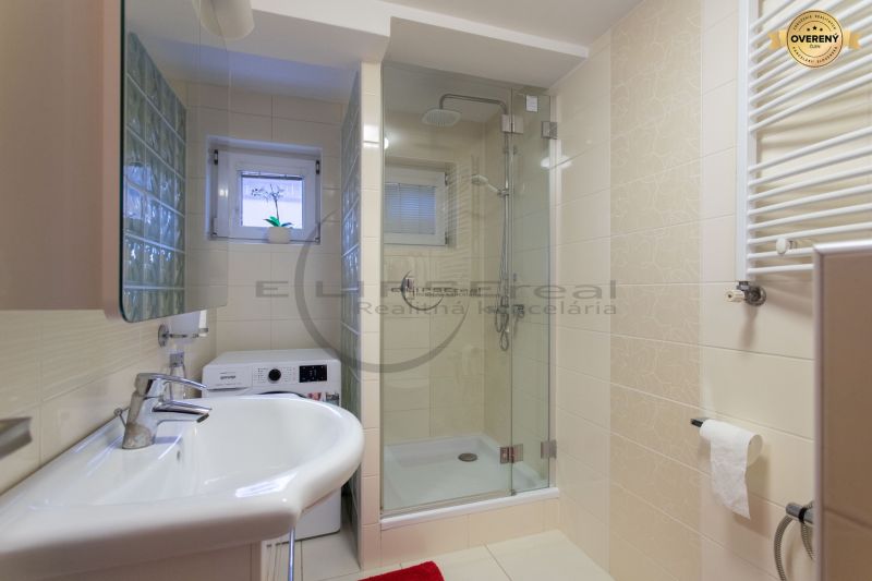 Badezimmer mit Toilette, Duschkabine und Waschmaschine in einem Einfamilienhaus.