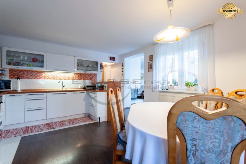 Eine Küche in einem Einfamilienhaus mit weißen Schränken, orangefarbenen Fliesen und einem Boden in Holzoptik.
