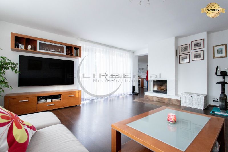 Wohnzimmer in einem Einfamilienhaus mit Kamin, Fernseher und Holzboden.