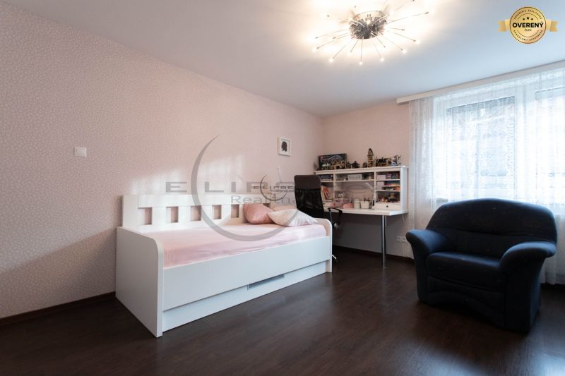 Kinderzimmer mit weißem Bett, Schreibtisch, Stuhl und Boden in Holzoptik.