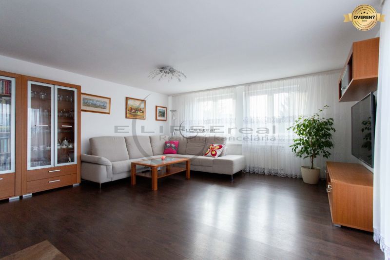 Wohnzimmer in einem Einfamilienhaus mit Sofa, Fernseher und Holzboden.