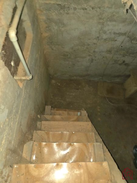 Eine Treppe, die in den Keller führt, mit Wänden, an denen sichtbare Rohre in den Gärten sind.