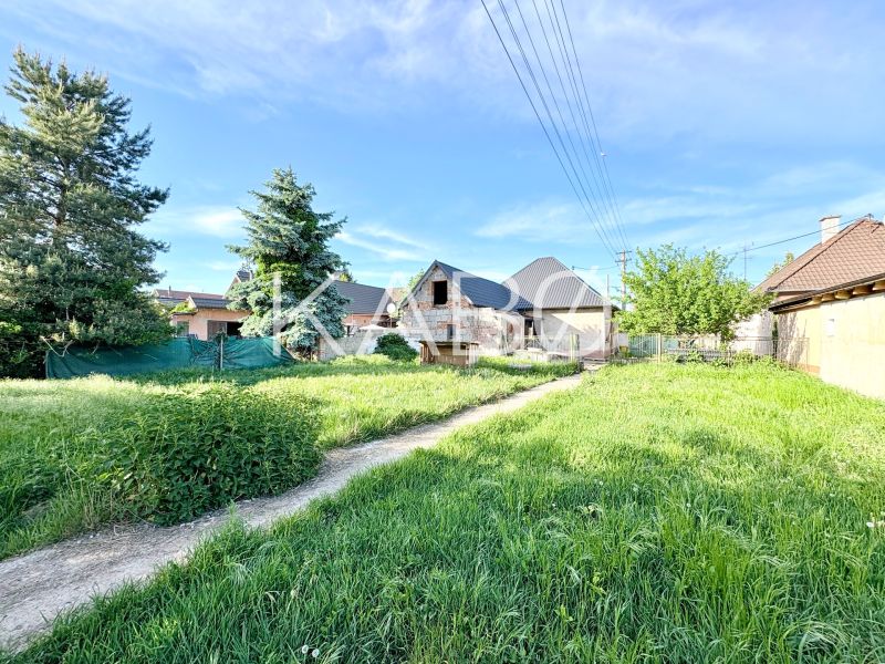 Baugrundstück in Šoporňa mit Blick auf die umliegende Grünfläche und Einfamilienhäuser.