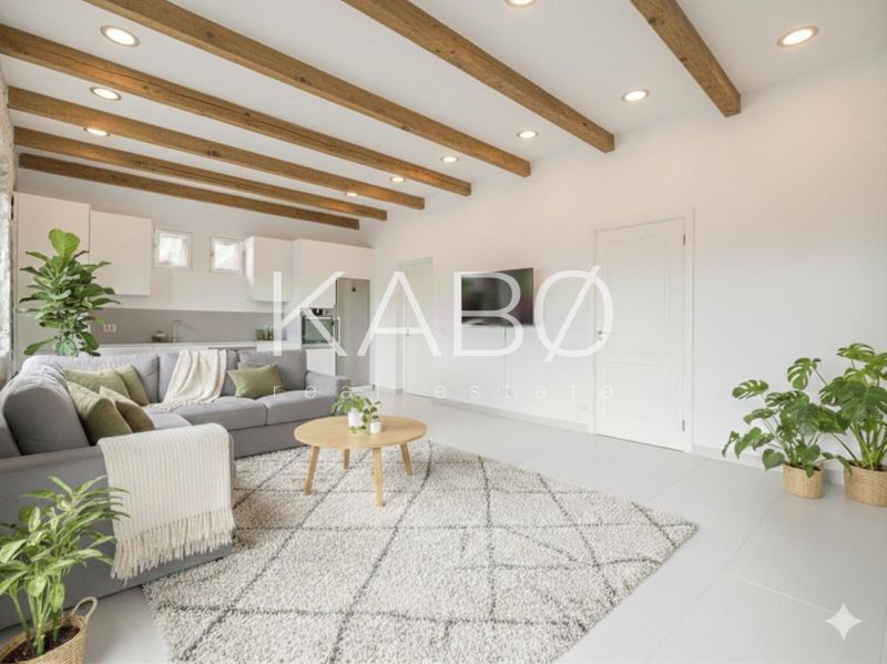 Wohnzimmer in einem Einfamilienhaus mit Balkendecke, Sofa und Pflanzen, Boden mit Holzdekor.