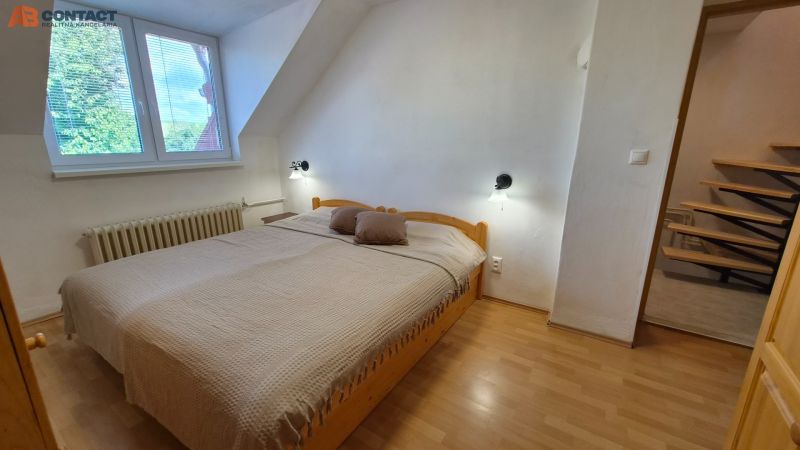 Schlafzimmer in einer 2-Zimmer-Wohnung mit Doppelbett und Boden in Holzoptik.