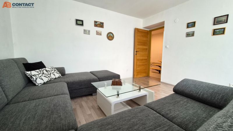Wohnzimmer in einer 2-Zimmer-Wohnung mit einem Sofa, einem Glastisch und einem Boden in Holzoptik.