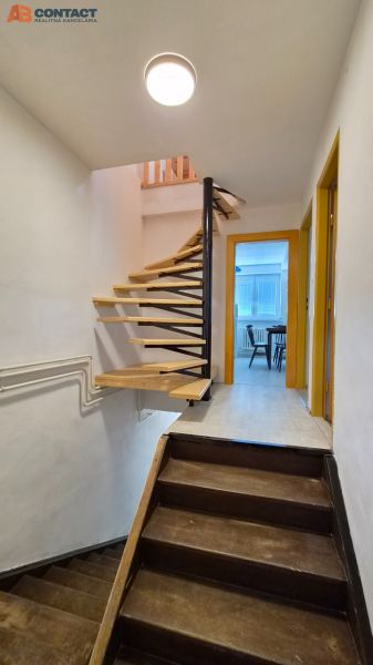 Interieur einer Maisonette-Wohnung mit Holztreppe und Eingang zu einem Raum.