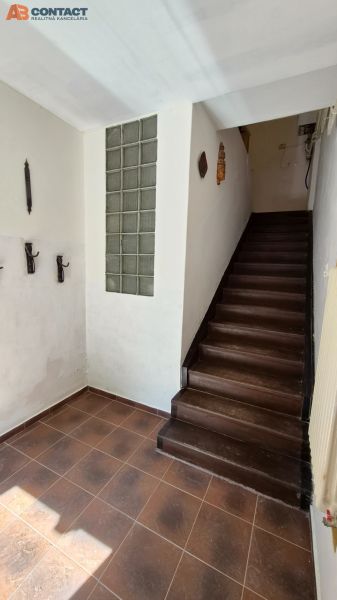 Ein Flur mit dunklen Treppen, die in die obere Etage einer 2-Zimmer-Wohnung führen.