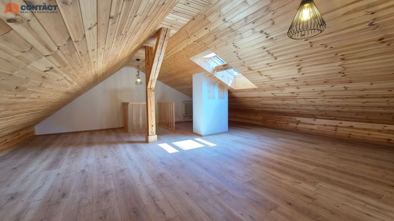 Ein Dachzimmer mit Holzverkleidung und einem Boden in Holzoptik.