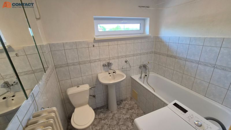 Badezimmer in einer 2-Zimmer-Wohnung mit Badewanne, Waschbecken, Waschmaschine und gefliesten Wänden.