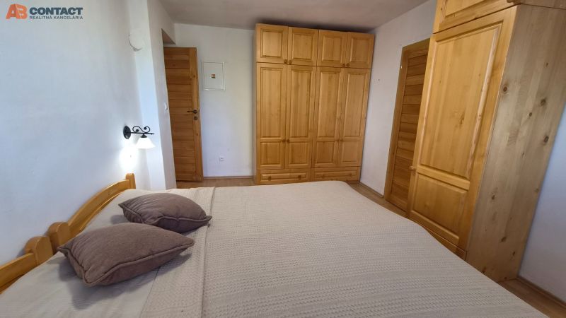 Schlafzimmer in einer 2-Zimmer-Wohnung mit Holzschränken, Bett und Boden mit Holzdekor.