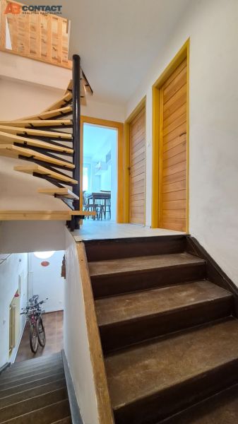 Eine Treppe mit einem hölzernen Geländer führt zu einer 2-Zimmer-Wohnung mit Blick auf die Eingangstür.