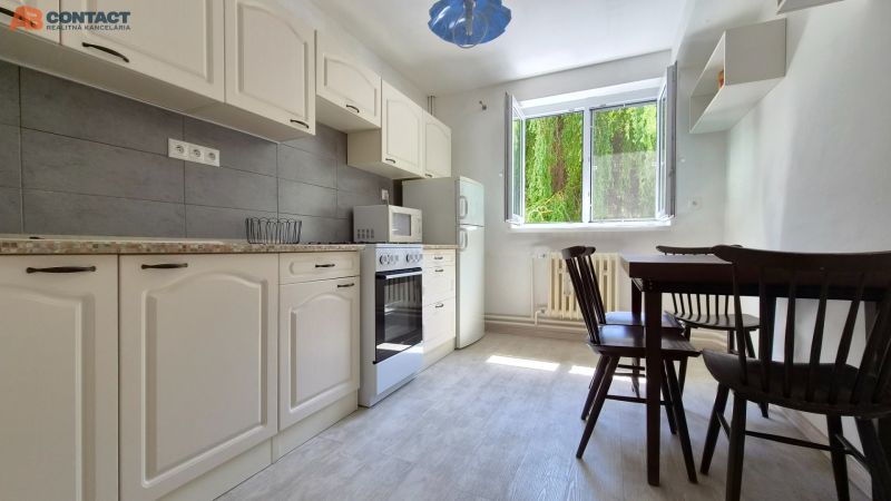 Küche mit weißen Schränken und Esstisch in einer 2-Zimmer-Wohnung.