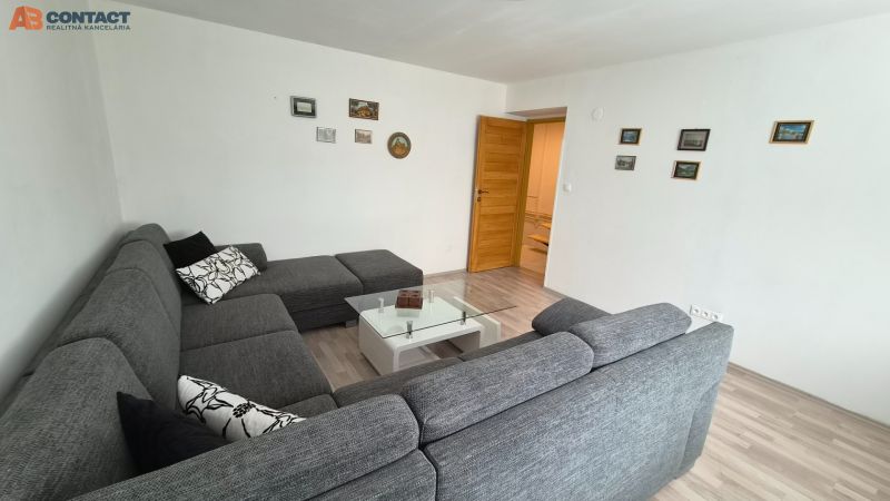 Wohnzimmer in einer Zweizimmerwohnung mit einem bequemen Sofa und einem Glastisch.