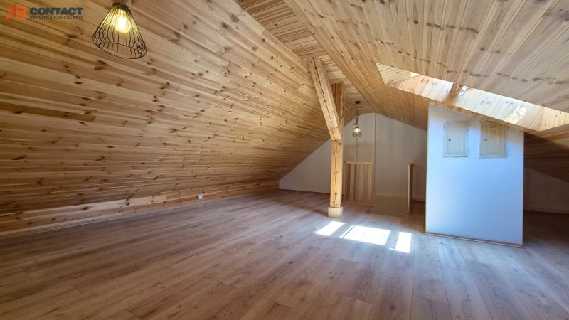 Dachgeschosszimmer in einer 2-Zimmer-Wohnung mit Holzboden und Holzverkleidung.